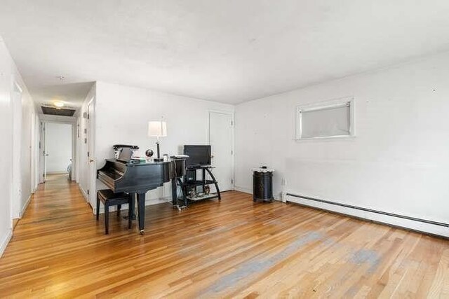 office space with light wood-type flooring and a baseboard heating unit