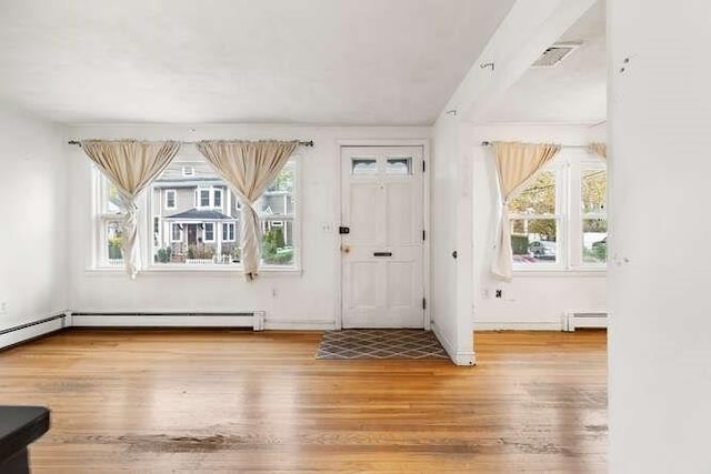 entryway with plenty of natural light, baseboard heating, wood finished floors, and visible vents
