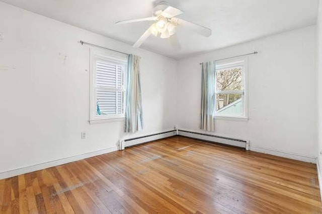 empty room featuring baseboards, ceiling fan, a baseboard heating unit, and wood finished floors