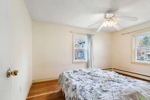 bedroom with baseboards, ceiling fan, wood finished floors, and multiple windows