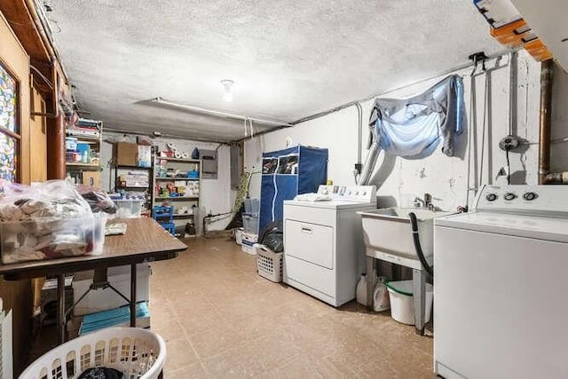 laundry room featuring laundry area, a sink, a textured ceiling, and washing machine and clothes dryer
