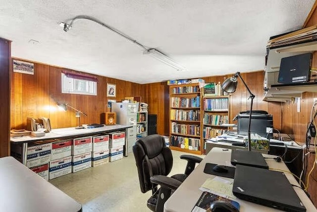 home office featuring wood walls, a textured ceiling, and concrete floors