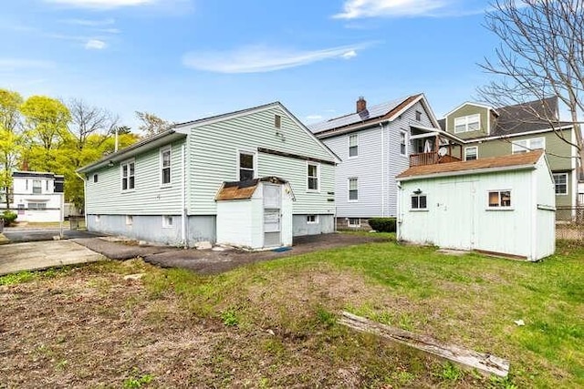 back of property with a storage unit, an outbuilding, and a yard