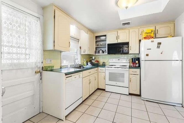 kitchen featuring dark countertops, tasteful backsplash, a sink, light tile patterned floors, and white appliances