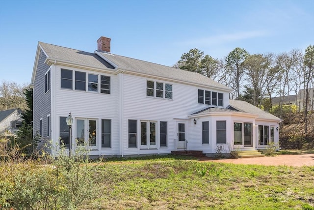 rear view of property with a chimney, entry steps, and a yard