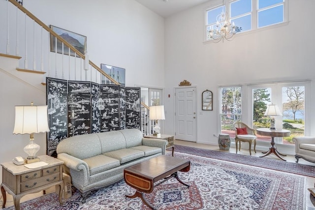 living room with a high ceiling, stairway, a chandelier, and baseboards
