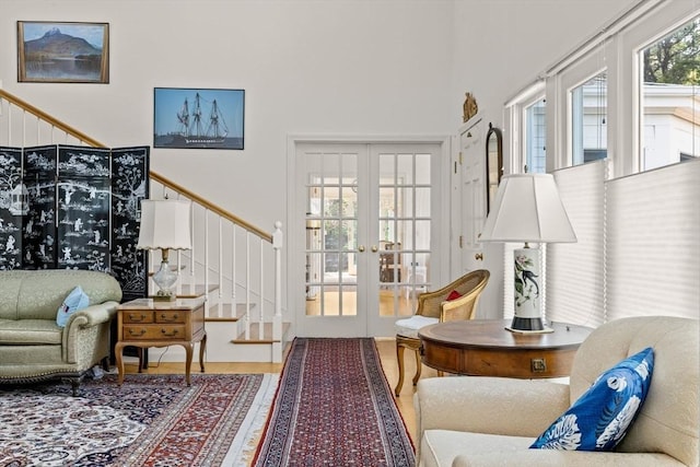 living room featuring french doors, stairs, wood finished floors, and a towering ceiling