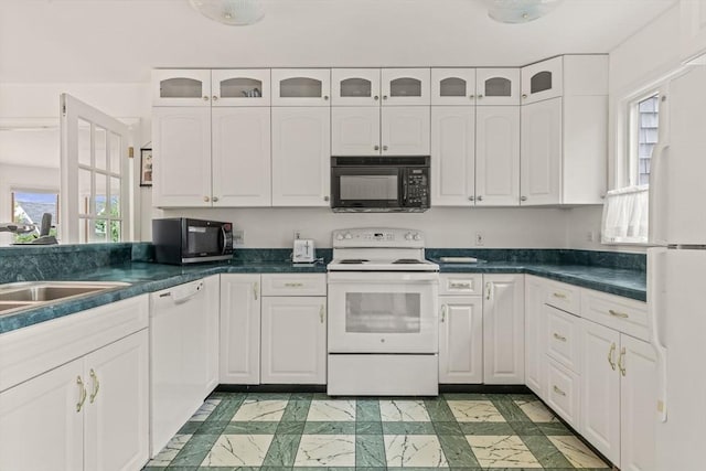 kitchen with white appliances, white cabinets, dark countertops, and healthy amount of natural light