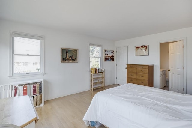 bedroom featuring light wood-style flooring and ensuite bath