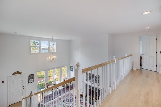 corridor with a chandelier, an upstairs landing, light wood-style flooring, and recessed lighting