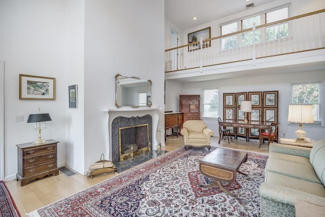 living area with a towering ceiling, wood finished floors, a fireplace, baseboards, and recessed lighting