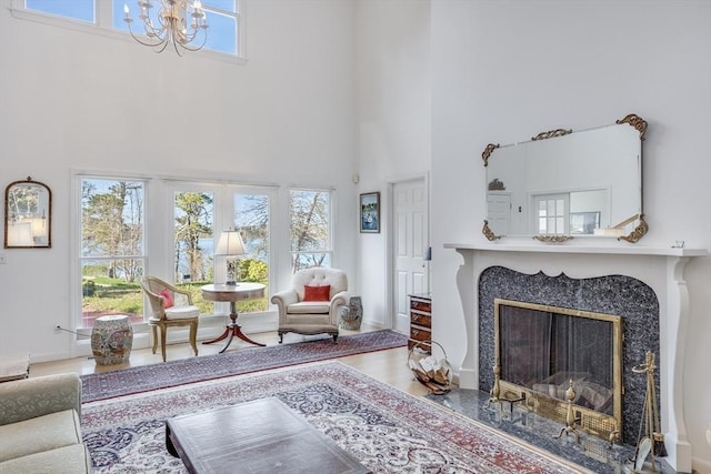 living area with a towering ceiling, a chandelier, a fireplace, and wood finished floors