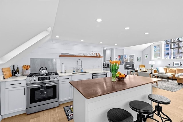 2111/2 Bradford St, Provincetown, MA 02657 - kitchen with appliances with stainless steel finishes, a sink, light wood-type flooring, open shelves, and decorative backsplash