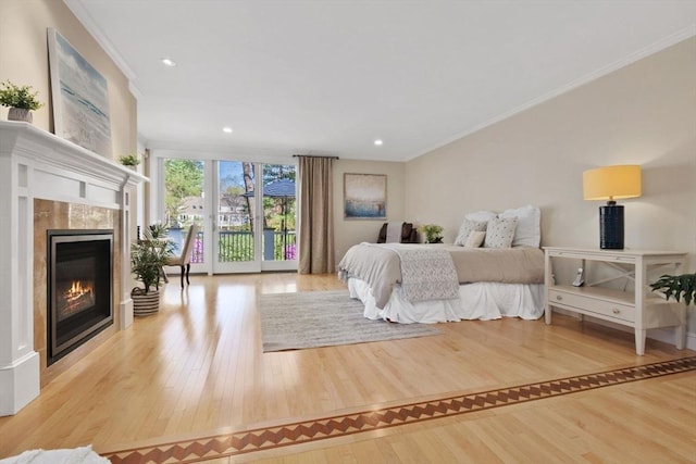 bedroom featuring access to outside, ornamental molding, wood finished floors, and a tile fireplace