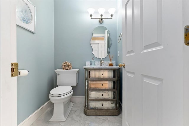 bathroom with toilet, baseboards, marble finish floor, and vanity
