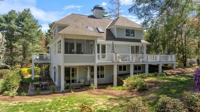 back of house featuring a patio, a chimney, roof with shingles, and a deck
