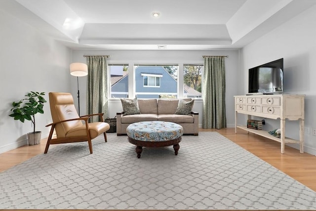 interior space with baseboards, a tray ceiling, and wood finished floors