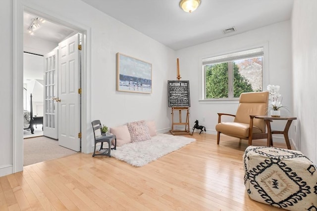 sitting room featuring baseboards, hardwood / wood-style flooring, and visible vents