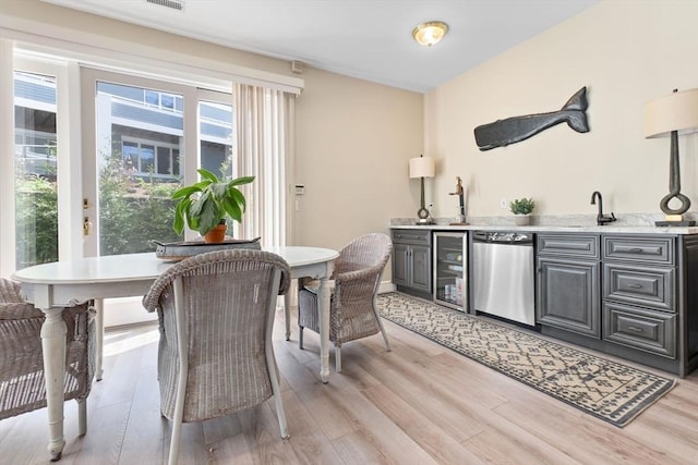 interior space featuring indoor wet bar, beverage cooler, and light wood-type flooring