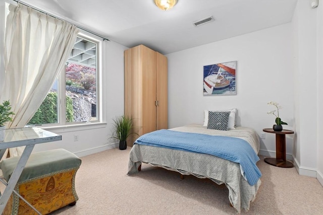bedroom featuring visible vents, baseboards, and light carpet