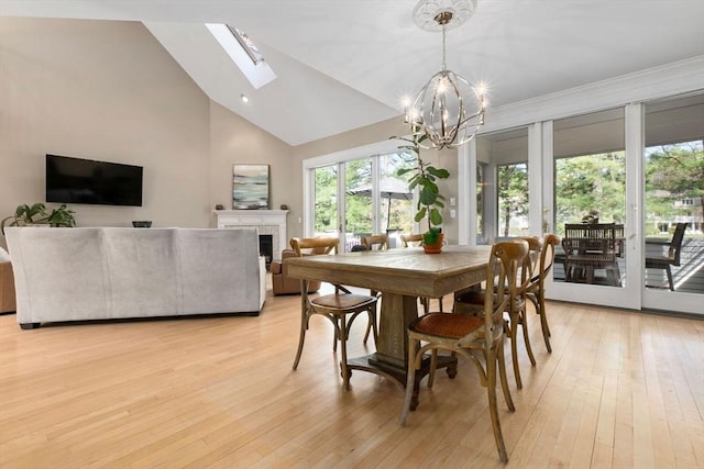 dining space featuring light wood-type flooring, a notable chandelier, a healthy amount of sunlight, and a tile fireplace