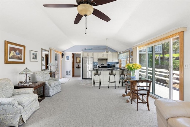 living area featuring a ceiling fan, light colored carpet, visible vents, and vaulted ceiling