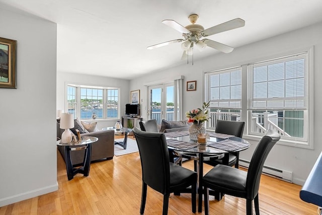 dining room with light wood finished floors, a ceiling fan, and baseboards