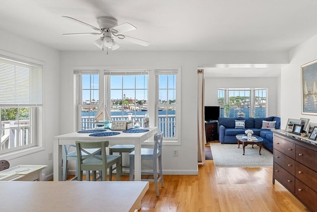 dining space with a ceiling fan, light wood-type flooring, and baseboards