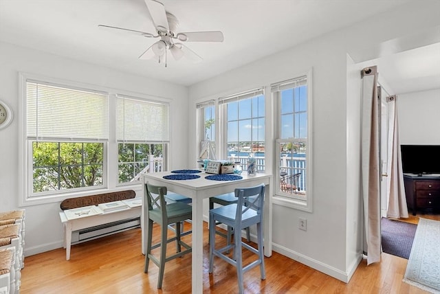 dining room featuring a baseboard heating unit, baseboards, light wood finished floors, and a ceiling fan