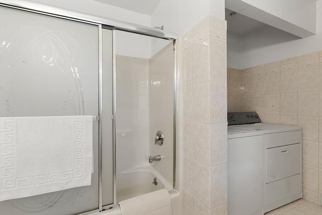 bathroom featuring tile patterned flooring, independent washer and dryer, tile walls, and bath / shower combo with glass door