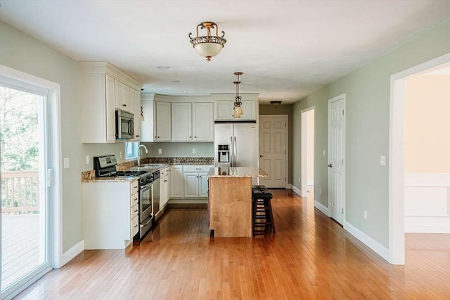 20 Warner Rd, Townsend, MA 01469 - kitchen with hardwood / wood-style floors, a breakfast bar area, light stone counters, a sink, and stainless steel appliances