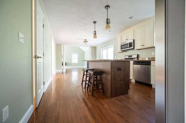 20 Warner Rd, Townsend, MA 01469 - kitchen with dark wood-style flooring, a breakfast bar area, a center island, stainless steel appliances, and baseboards