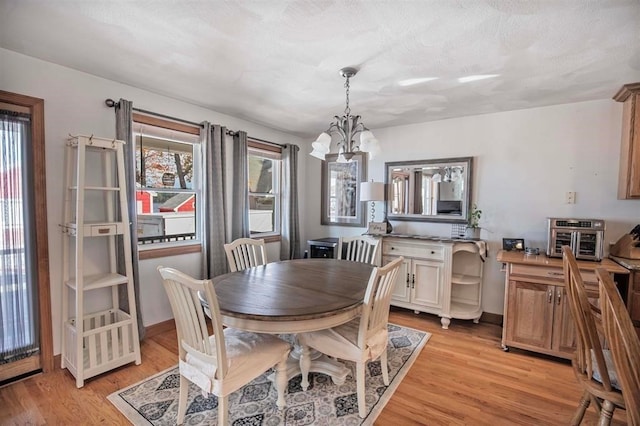 dining space with light hardwood / wood-style floors, a notable chandelier, and a textured ceiling