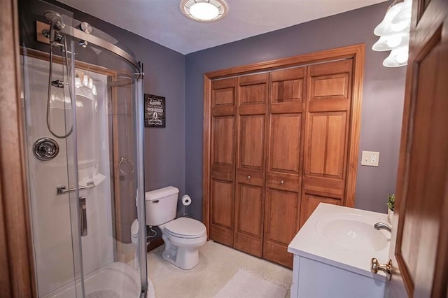 bathroom with toilet, vanity, and a shower with door