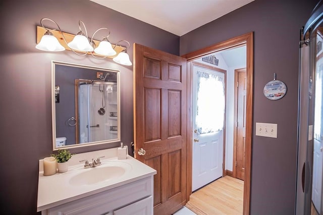 bathroom with hardwood / wood-style floors, vanity, toilet, and a shower with door