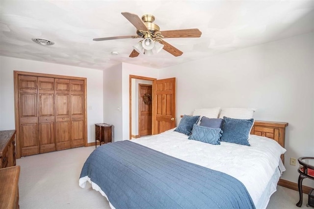 bedroom featuring light carpet, ceiling fan, and a closet