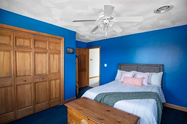 bedroom with a closet, dark colored carpet, and ceiling fan