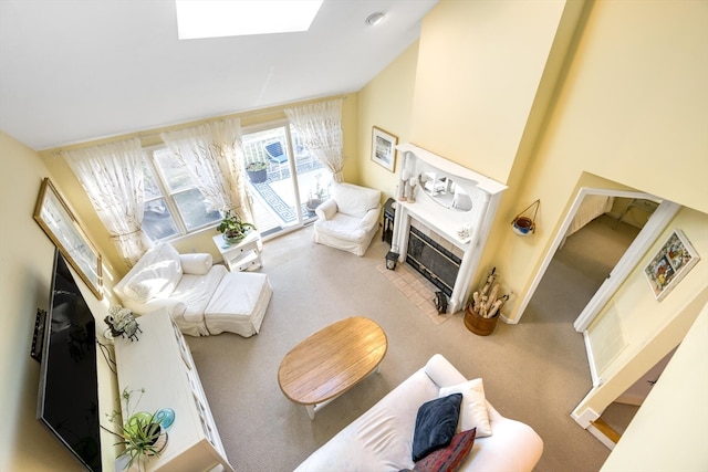 living room featuring a tile fireplace, light colored carpet, high vaulted ceiling, and a skylight