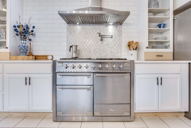 kitchen featuring wall chimney range hood, white cabinetry, double oven range, tasteful backsplash, and light tile patterned flooring