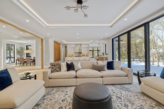 living room featuring expansive windows, a tray ceiling, and an inviting chandelier