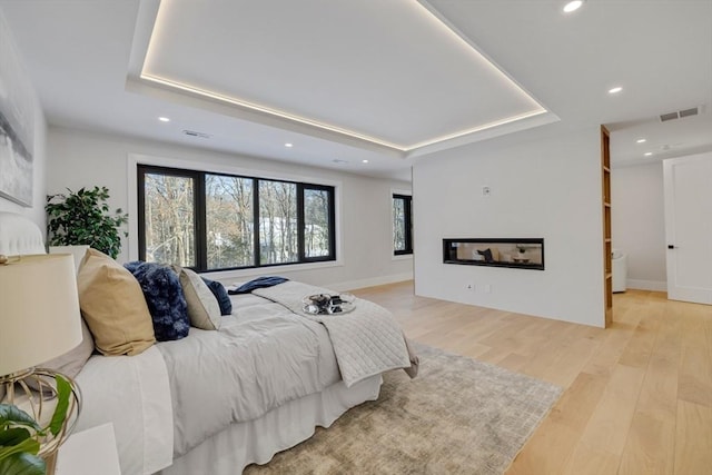 bedroom featuring a tray ceiling and light hardwood / wood-style floors