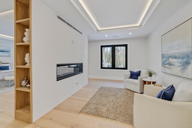 living room with hardwood / wood-style flooring and a raised ceiling