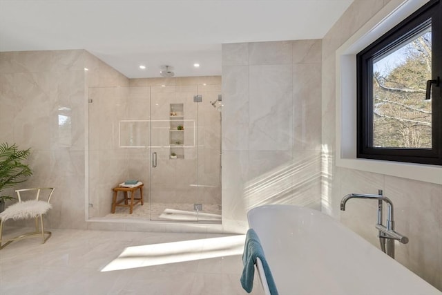 bathroom with a shower with door and tile walls