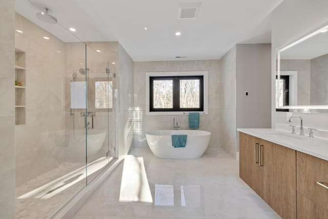 bathroom featuring tile walls, vanity, and plus walk in shower