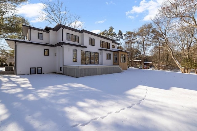 snow covered rear of property featuring central AC