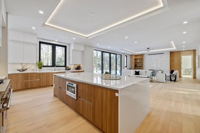 kitchen with plenty of natural light, a large island, white cabinets, and a tray ceiling