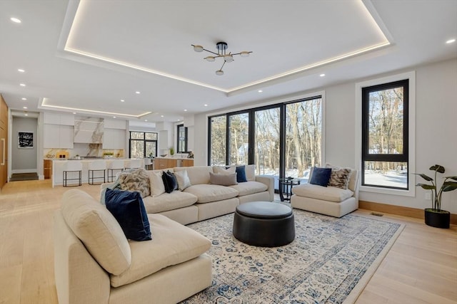 living room with light hardwood / wood-style flooring and a tray ceiling