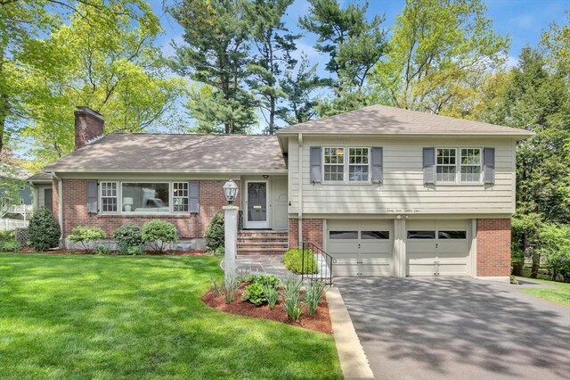 27 Lantern Ln, Arlington, MA 02474 - tri-level home with driveway, an attached garage, a chimney, a front yard, and brick siding