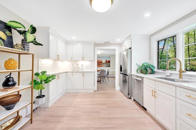 27 Lantern Ln, Arlington, MA 02474 - kitchen featuring a sink, appliances with stainless steel finishes, backsplash, light countertops, and white cabinetry