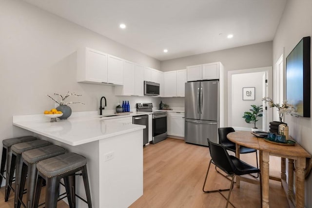 1 Cross St Unit 205, Wilmington, MA 01887 - kitchen with stainless steel appliances, a sink, a peninsula, a kitchen breakfast bar, and light countertops